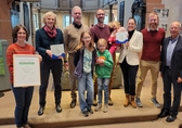 Mitglieder der Ev. Kirchengemeinde halten Auszeichnung "Grüner Hahn" in die Kamera