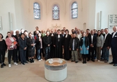 Gruppenfoto der Finanzverantwortlichen aus 25 internationalen Kirchen und fünf Missionsgesellschaften. Sie stehen im Halbkreis innerhalb einer Kirche. Im Hintergrund: bunte Kirchenfenster