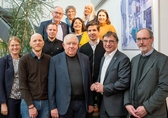 Vertreter der Firma Herbert und der Ev. Kirche in Hessen und Nassau stehen in 4 Reihen hintereinander auf einer Treppe