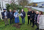 Vertreterinnen und Vertreter von neun Religionsgemeinschaften stehen um einen frisch gepflanzten Kirschbaum