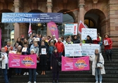 Menschen stehen mit Plakaten auf den Stufen des Wiesbadener Rathauses und demonstrieren für eine zukunftsfähige Sozialpolitik
