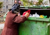 Alte Frau such nach essbaren Lebensmitteln im Müllcontainer