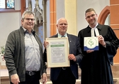 3 Personen stehen nebeneinander und halten die Auszeichnung Grüner Hahn in die Höhe